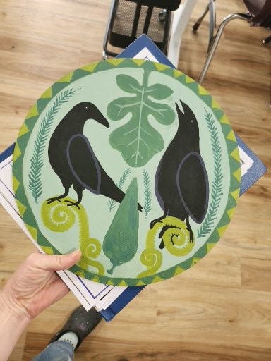 a green hex sign with crows, ferns, and greenery